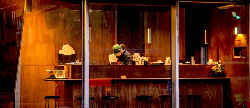 夕暮れの窓越しに見える、あかりの灯った店内